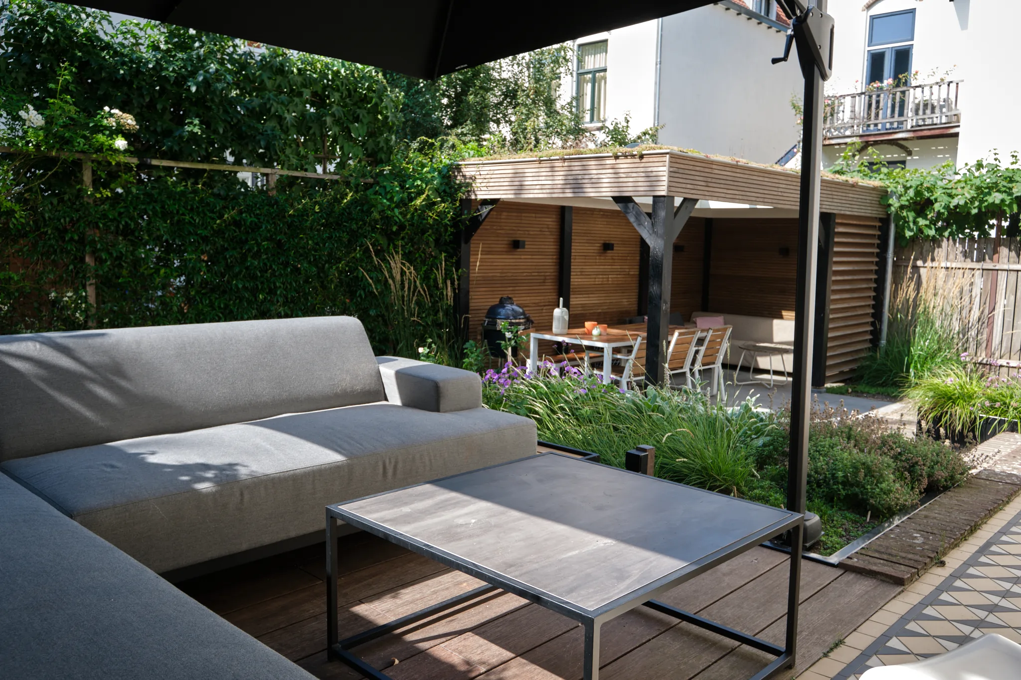 Zicht vanuit lounge hoek naar houten paviljoen met eethoek