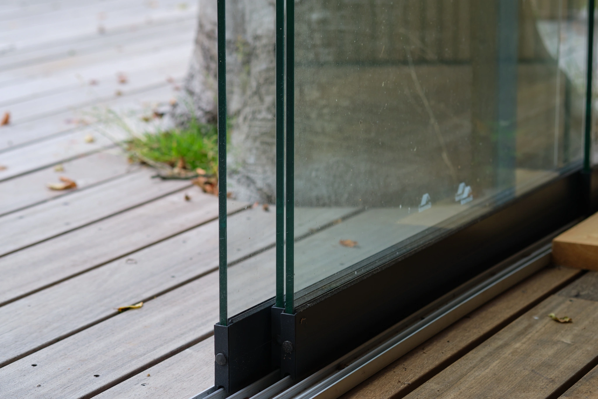 Detail van glazen schuifdeur rail systeem op houten vlonder