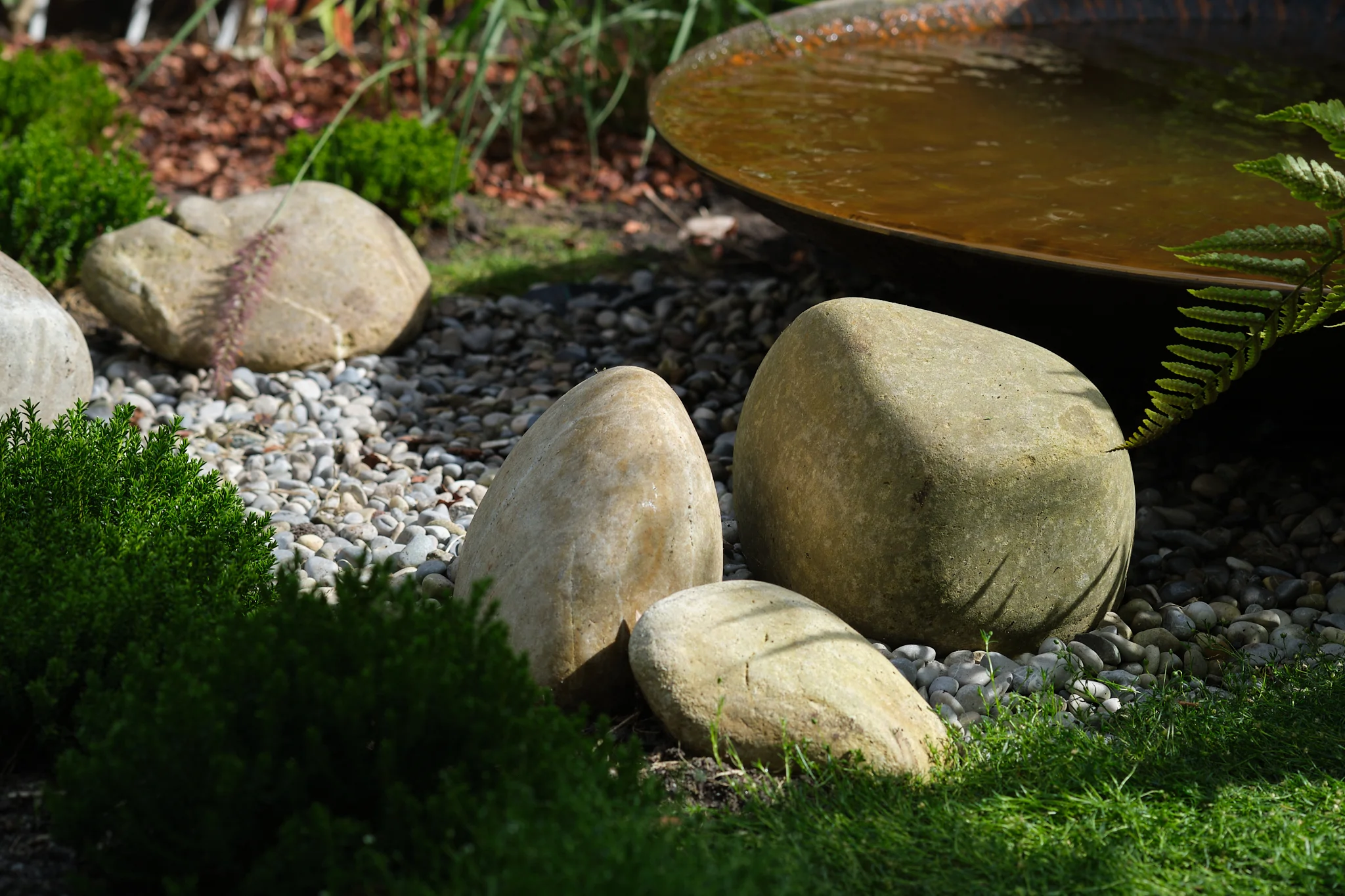 Natuurstenen keien rond waterpartij met varens en kiezels