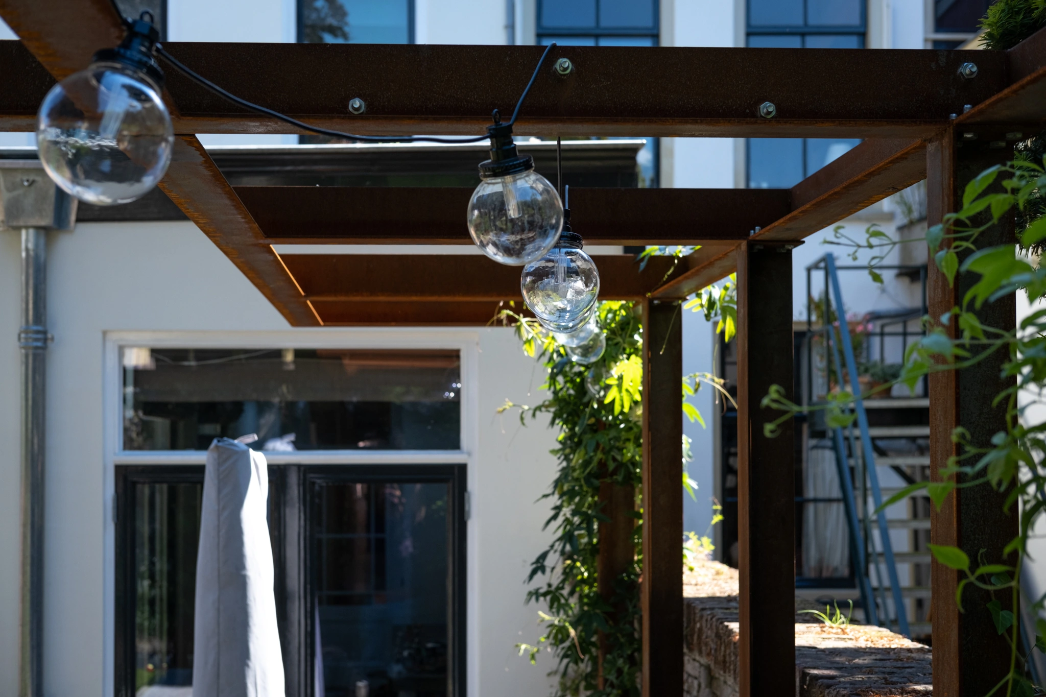 Moderne houten pergola met geïntegreerde LED-verlichting en glazen hanglampen