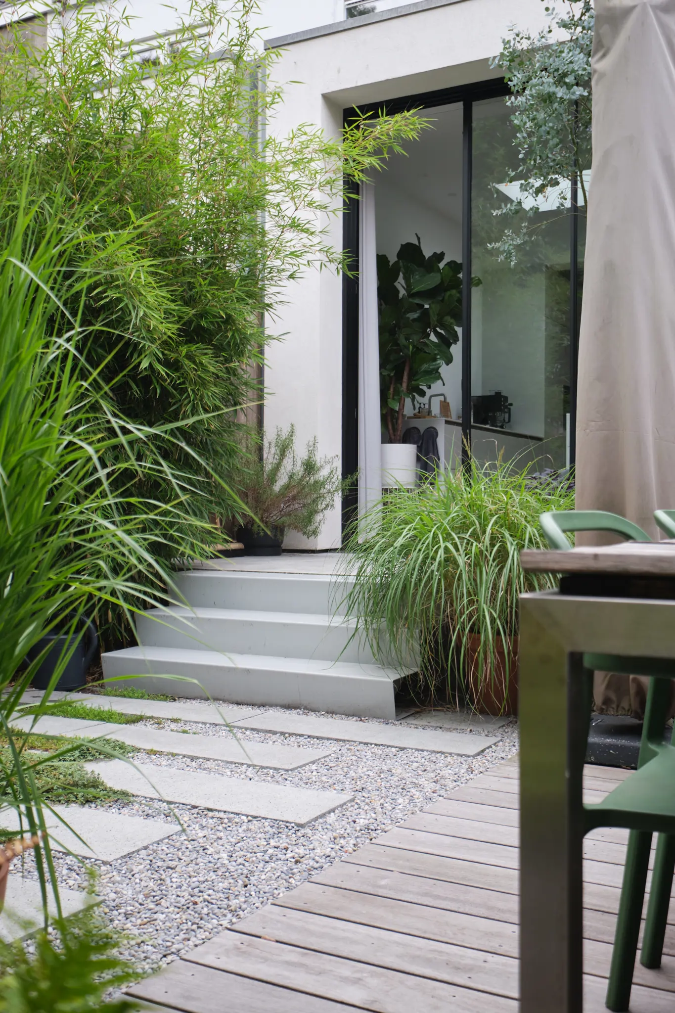 Moderne entree met witte trappen en weelderige bamboe beplanting