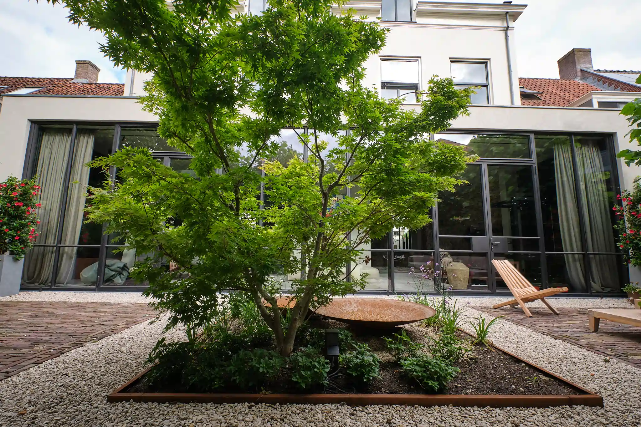 Centrale binnenplaats met Japanse esdoorn in geometrische plantenbak
