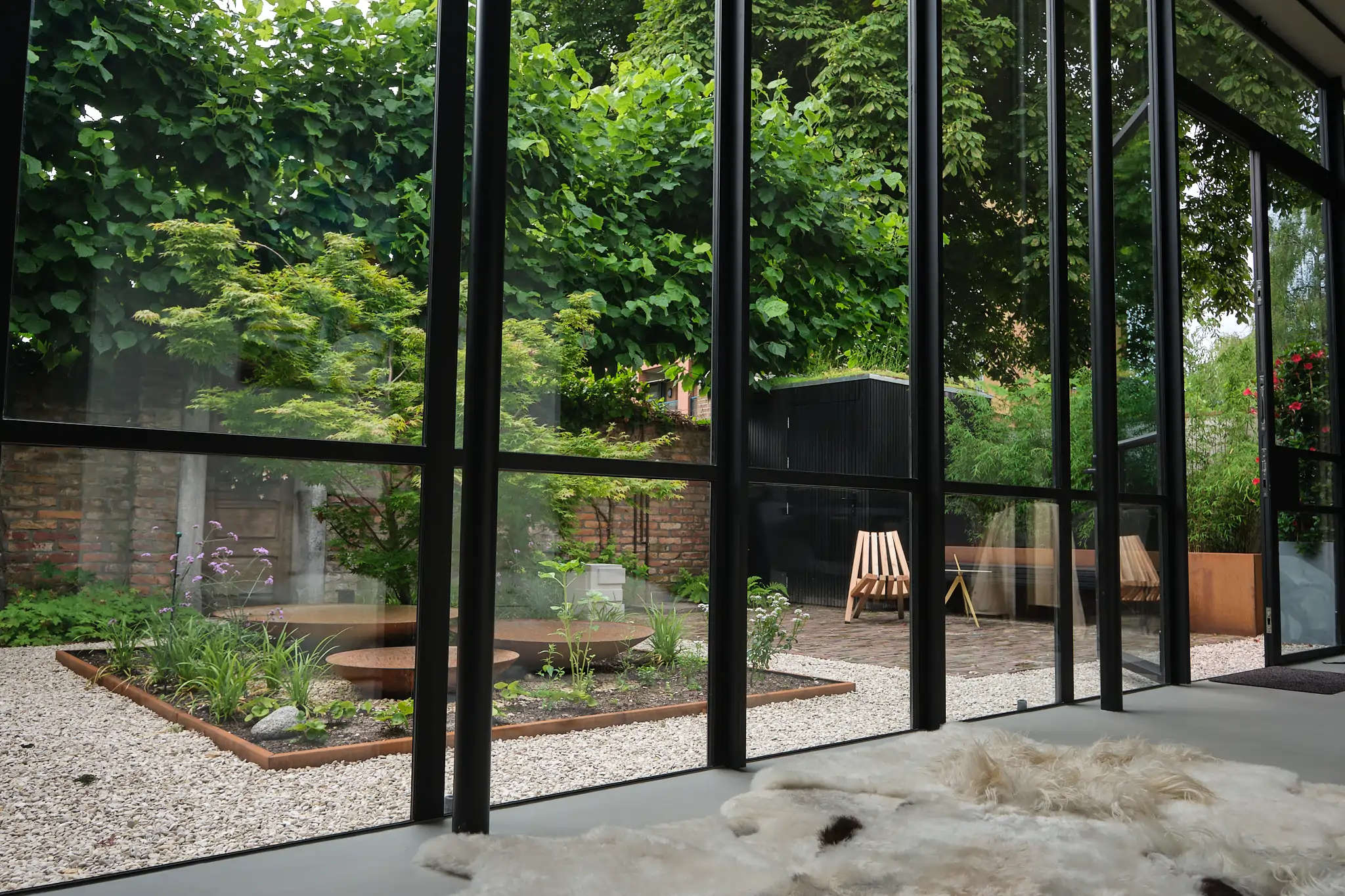 Interieur uitzicht door stalen ramen naar complete tuinontwerp